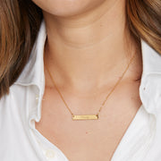 model wearing engraved necklace, engraved with the name Emily in a script font