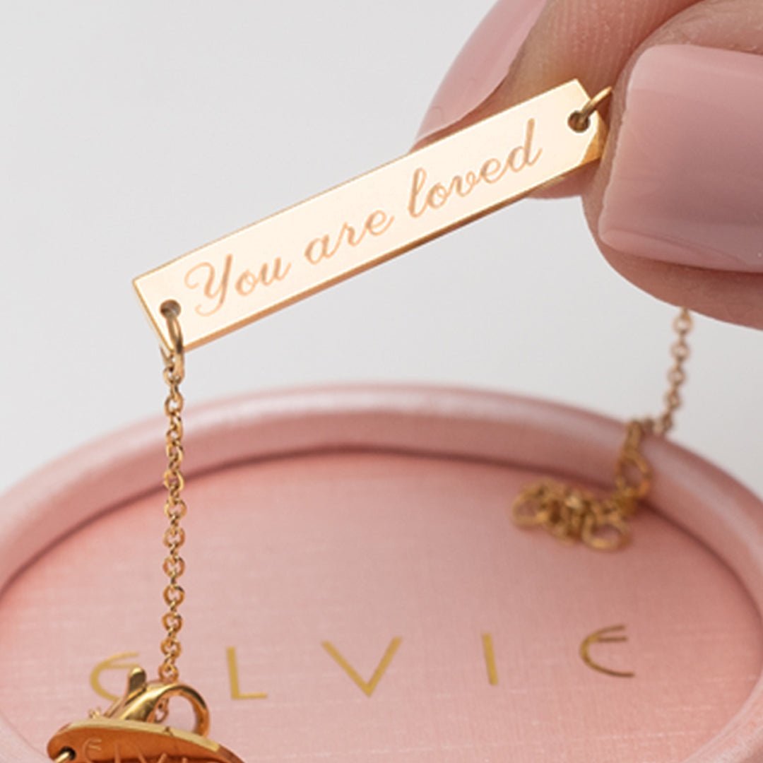 Gold engraved necklace engraved with the phrase "You are loved"