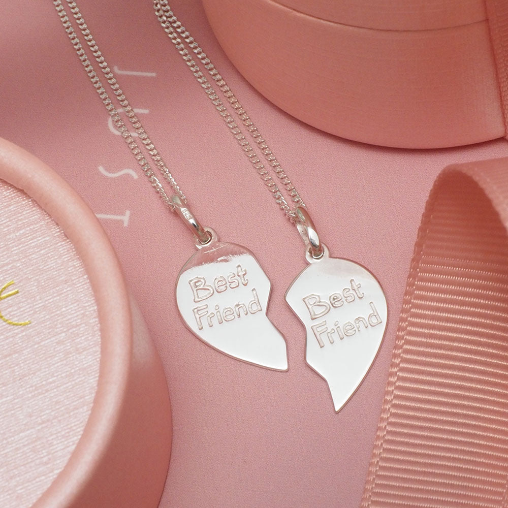 Close-up of ELVIE's Best Friend Necklaces in 925 sterling silver. The set of two necklaces features "BEST FRIEND" engraving on the front and customizable initials on the back, with delicate chains and iconic pink gift boxes, embodying a cool, effortlessly sexy, chic, and modern style.